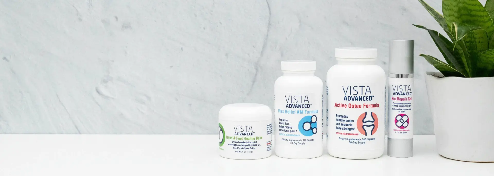 Five Vista Advanced supplement bottles in varying sizes are lined up against a light background. A green potted plant is on the right, adding a fresh touch.